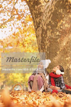 Girls Sitting And Enjoying Near Tree Trunk