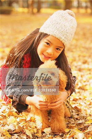 Fille avec un chien caniche en feuilles