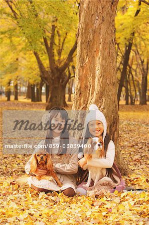 Girls Holding Their Dog In Leaves