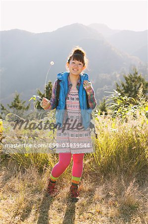 A Young Woman Holding A Dandelion Flower Outdoors