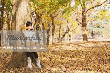 Girl Standing Against A Tree Holding Maple Leaf