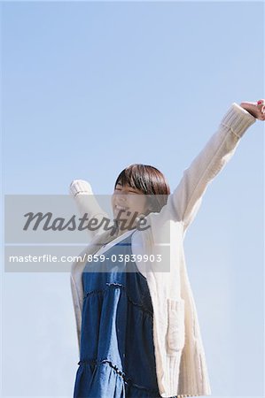 Japanese Teenage Girl Against Blue Sky Arms Outstretched