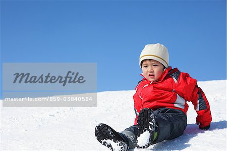 Junge Rutschen nach unten im Schnee