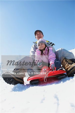 Father And Daughter sledging In Snow
