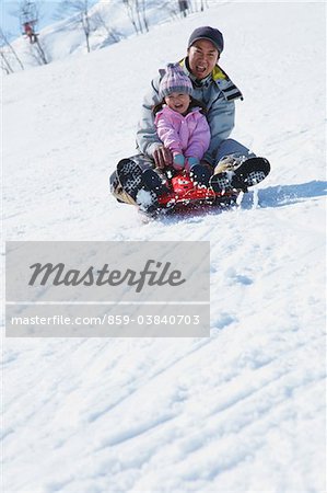 Father And Daughter sledging In Snow