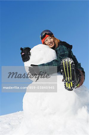 Young Woman With Snowman In Snow