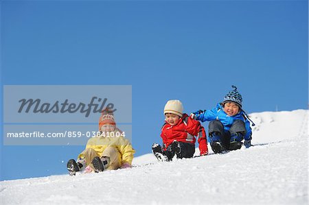 Kinder im Schnee zusammen nach unten schieben