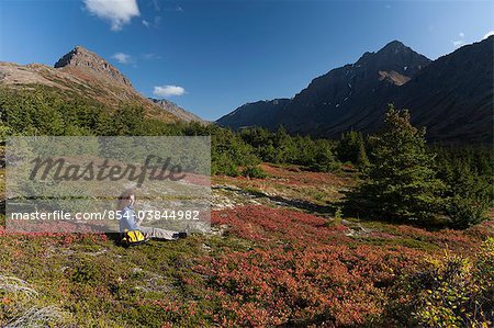 Woman hiker resting and enjoying the view in the Glen Alps area of Chugach State Park, Hidden Lake and the Ramp Trail, Chugach Mountains, Southcentral Alaska, Autumn