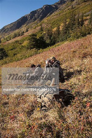 Two male moose hunters scope and glass for game in the Bird Creek drainage area, Chugach Mountains, Chugach National Forest, Southcentral Alaska, Autumn