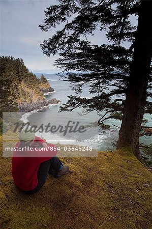 Female hiker resting and enjoying the view overlooking Chiniak Bay at Fort Abercrombie State Historical Park on Kodiak Island, Southwest Alaska, Fall