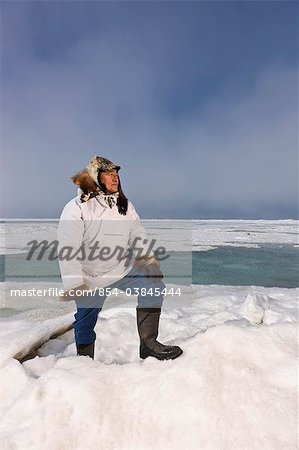 Chasseur de Inupiaq Eskimo mâle debout sur une crête de pression de glace tout en portant une parka traditionnelle des Esquimaux (Atigi) et seal skin hat, mer des Tchouktches près de Barrow, Alaska arctique, été