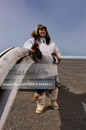 Mâle chasseur Inupiaq Eskimo debout derrière une baleine boréale le long de la mer des Tchouktches portant son parka (Atigi) esquimau, chapeau de peau de phoque et de loup Maklak la peau avec des semelles en peau de phoque barbu (Ugruk), de Barrow, Alaska arctique, été