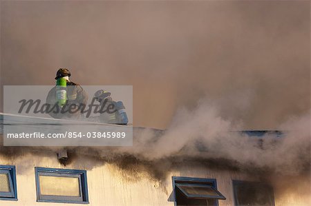 Zwei Feuerwehrmänner in Anchorage Feuerwehr stand auf dem Dach ein Innenstadt Motel während der Arbeit zu löschen die Blaze, South Central Alaska, Winter