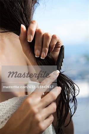 Woman combing wet hair, cropped