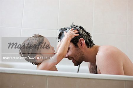 Garçon bébé cheveux du père à laver dans le bain