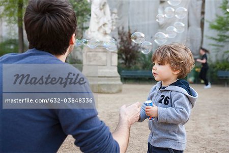 Fils père et enfant en bas âge jouer avec bulles