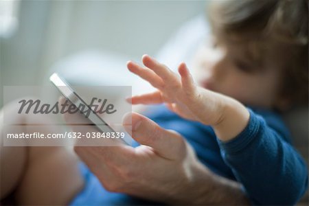 Toddler touching father's cell phone