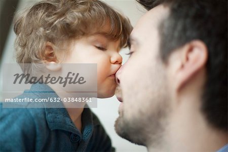 Toddler boy kissing father's nose
