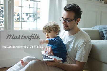 Father and young son looking at laptop computer together