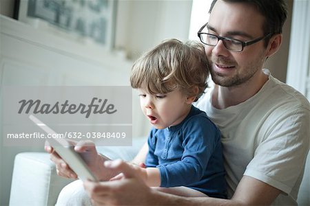 Père regarder bambin garçon, à l'aide de la tablette numérique avec une expression de surprise