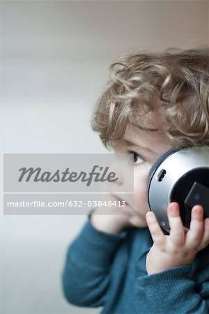Garçon de bambin à l'écoute de musique avec un casque, portrait