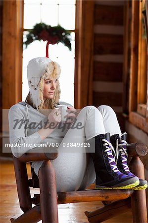 Woman with Mug Sitting in Chair in Cabin