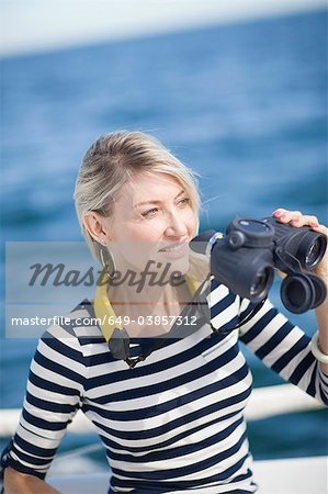 Femme à l'aide de jumelles sur bateau