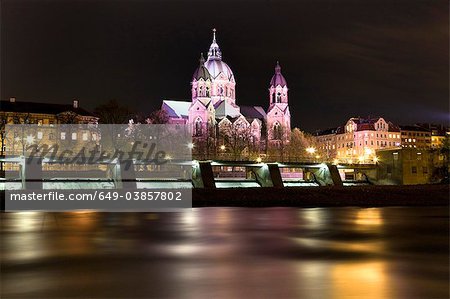 Beleuchtete Kirche und Brücke am Fluss in der Nacht