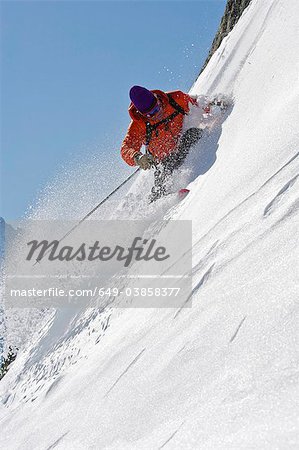 Skieur en tournant sur le visage de la montagne escarpée