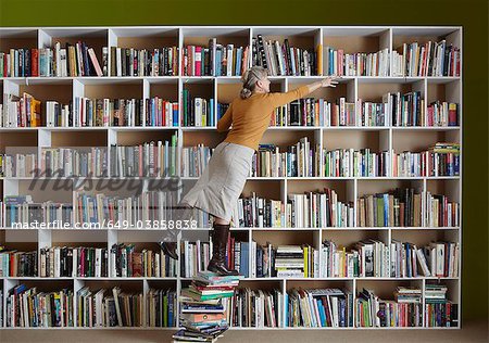 Ältere Frau stehend auf einem Stapel von Büchern