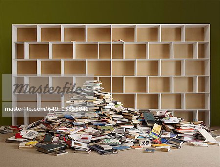 Pile of books by empty shelves