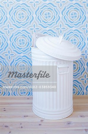 White dustbin against blue patterned wallpaper
