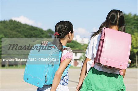 Enfants d'âge scolaire avec le sac d'école à pied à l'extérieur ensemble