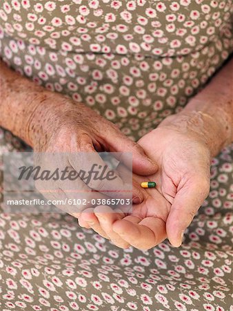 An elderly woman holding a pill, Sweden.