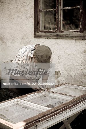 Un vieil homme, rénovation d'une fenêtre, Gotland, Suède.