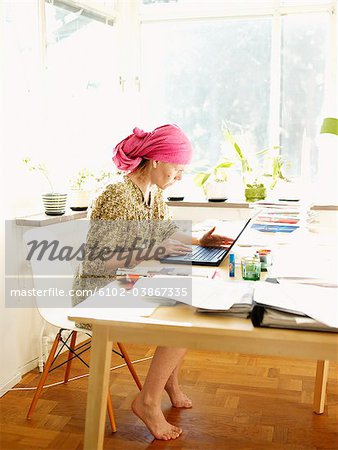 A woman using a laptop sitting in the living room, Sweden.