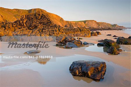 Golden evening light illuminates a deserted Sandymouth Bay in North Cornwall, England, United Kingdom, Europe