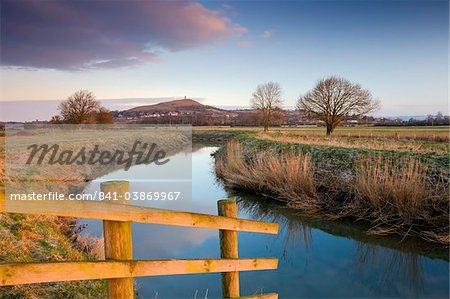 First light of a winter morning on Glastonbury Tor viewed from the River Brue on the Somerset Levels, Glastonbury, Somerset, England, United Kingdom, Europe