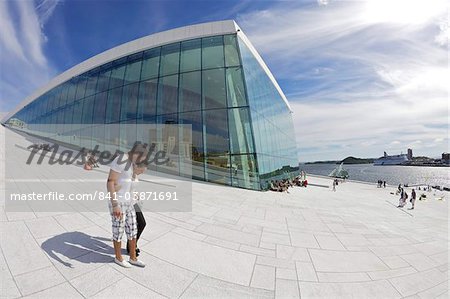 Young couple walking outside the Oslo Opera house exterior in summer sunshine, city centre, Oslo, Norway, Scandinavia, Europe