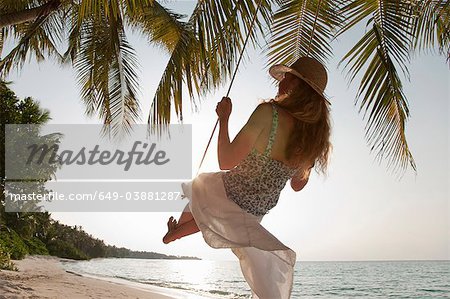 Woman swinging on tropical beach