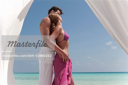 Couple s'enlaçant sur une plage tropicale