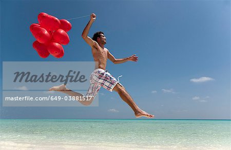 Homme sautant avec des ballons sur la plage