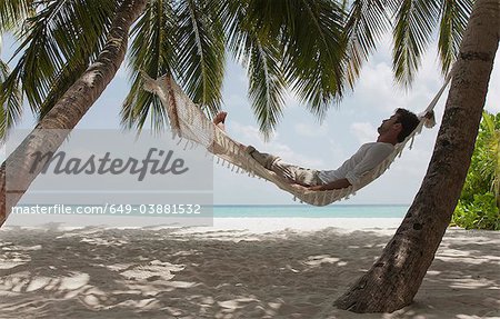 Homme pose en hamac sur la plage