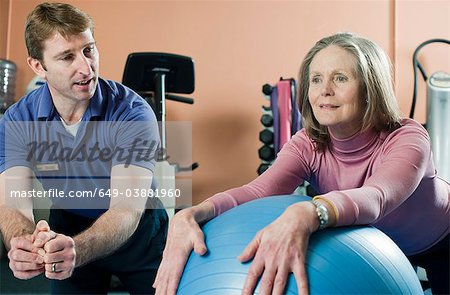 Trainer helping older woman exercise