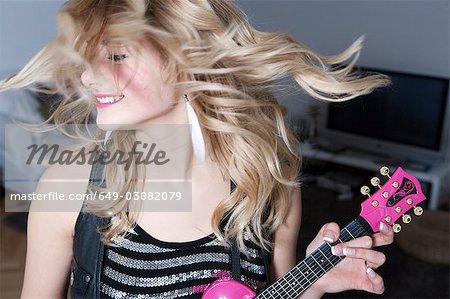 Teenage girl holding guitare miniature