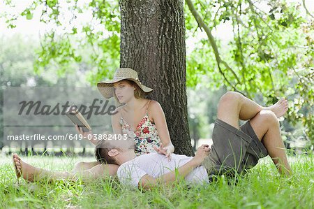 Couple relaxing under tree together