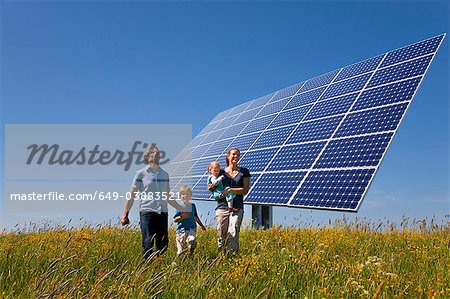 Famille marchant dans le champ de panneaux solaires