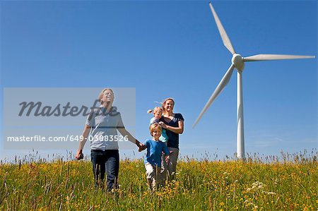 Famille marchant dans le champ par éolienne