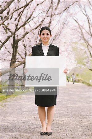 Femme d'affaires détenant un tableau blanc avec des fleurs de la cerise en arrière-plan