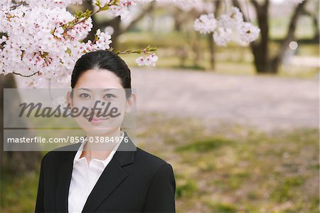 Businesswoman Standing In Field Of Cherry Blossom Tree Pointing Up